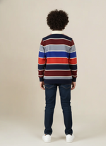 Person wearing a striped sweater and jeans on a plain background