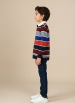 Child wearing a striped sweater and dark jeans on a beige background