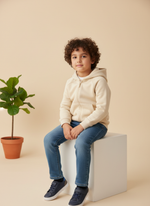 Child sitting on a white block with a plant in the background