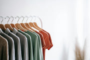 Row of colorful shirts on wooden hangers against a white background