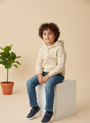Child sitting on a white block with a plant in the background