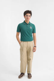 Person wearing a green polo shirt and beige pants on a white background