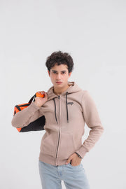 Man wearing a beige hoodie with a brand logo, holding an orange bag on a white background