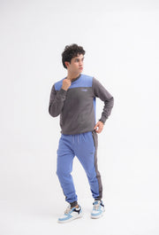 Person wearing a gray and blue tracksuit on a white background